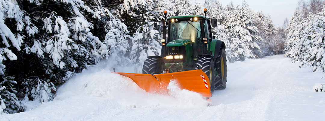 Traktor ausgestattet mit Schneepflug beim Schneeräumen